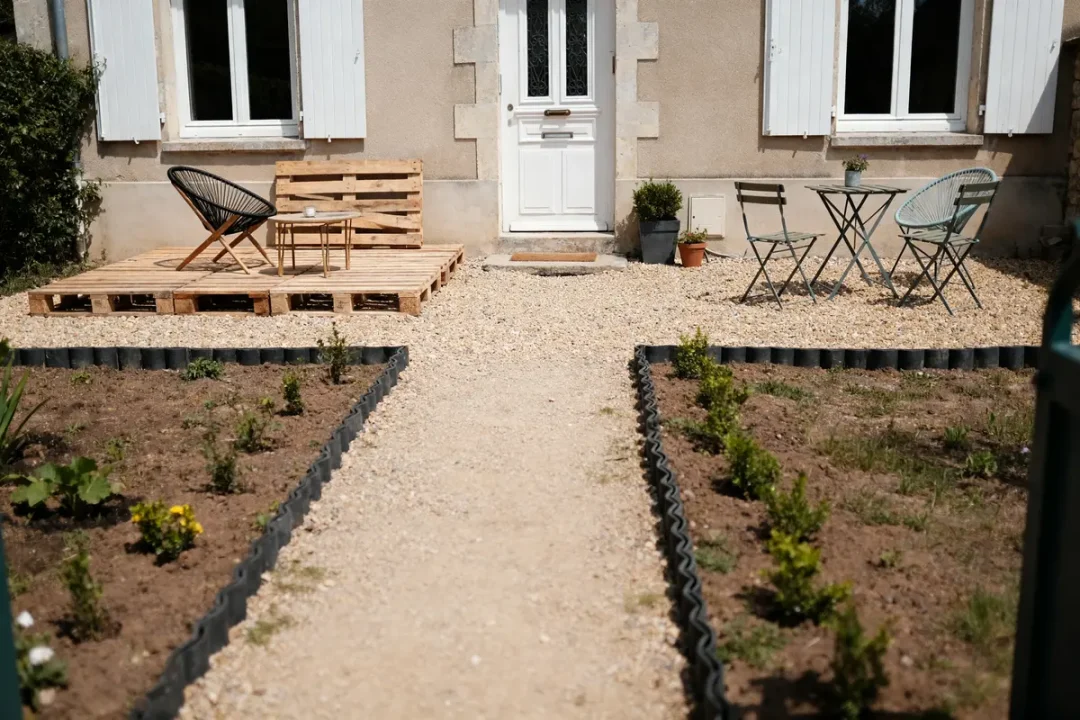 Aménagement pas cher devant maison avec terrasse en palettes et petits arbustes plantés