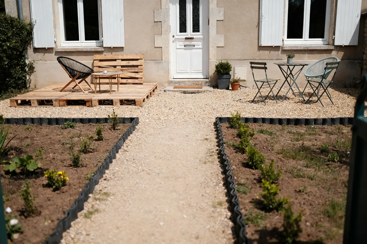 Aménagement pas cher devant maison avec terrasse en palettes et petits arbustes plantés