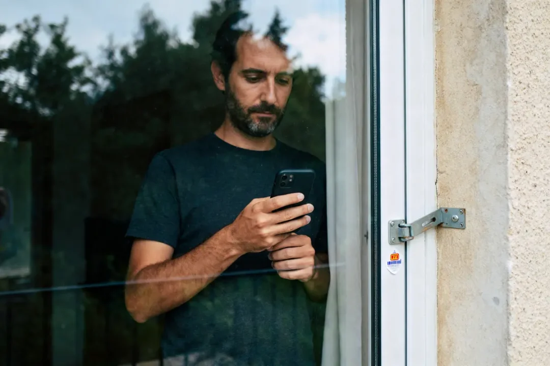 Homme utilisant un téléphone, mécanisme pour bloquer des portes coulissantes visible à droite